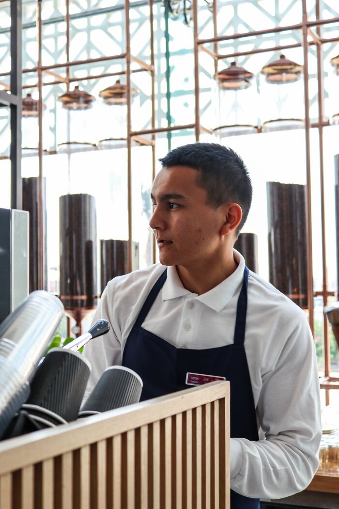 A barista at a coffee counter, looking to the side.