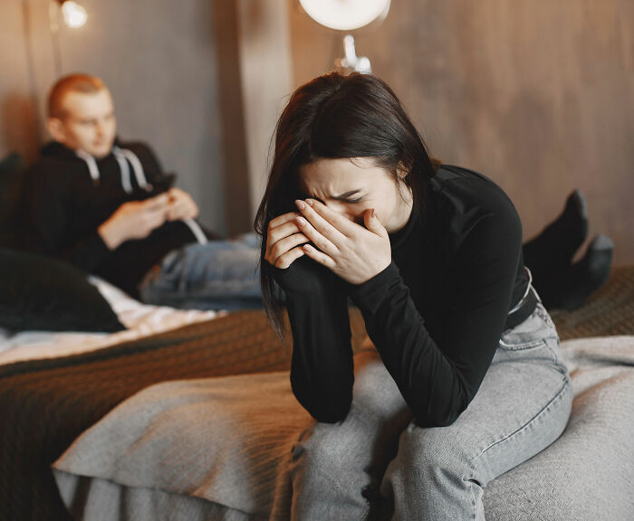 Woman crying with a man in the background, representing the man who married his cousin asking the internet for advice. Woman crying with a man in the background, representing the man who married his cousin asking the internet for advice.