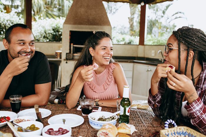 Newcomers to America enjoying a meal together, reflecting the diverse experiences that surprise those new to the country.