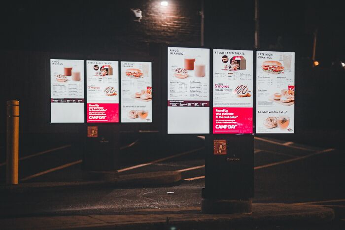 Brightly lit menu boards at a drive-through at night, showing crazy things customers said.