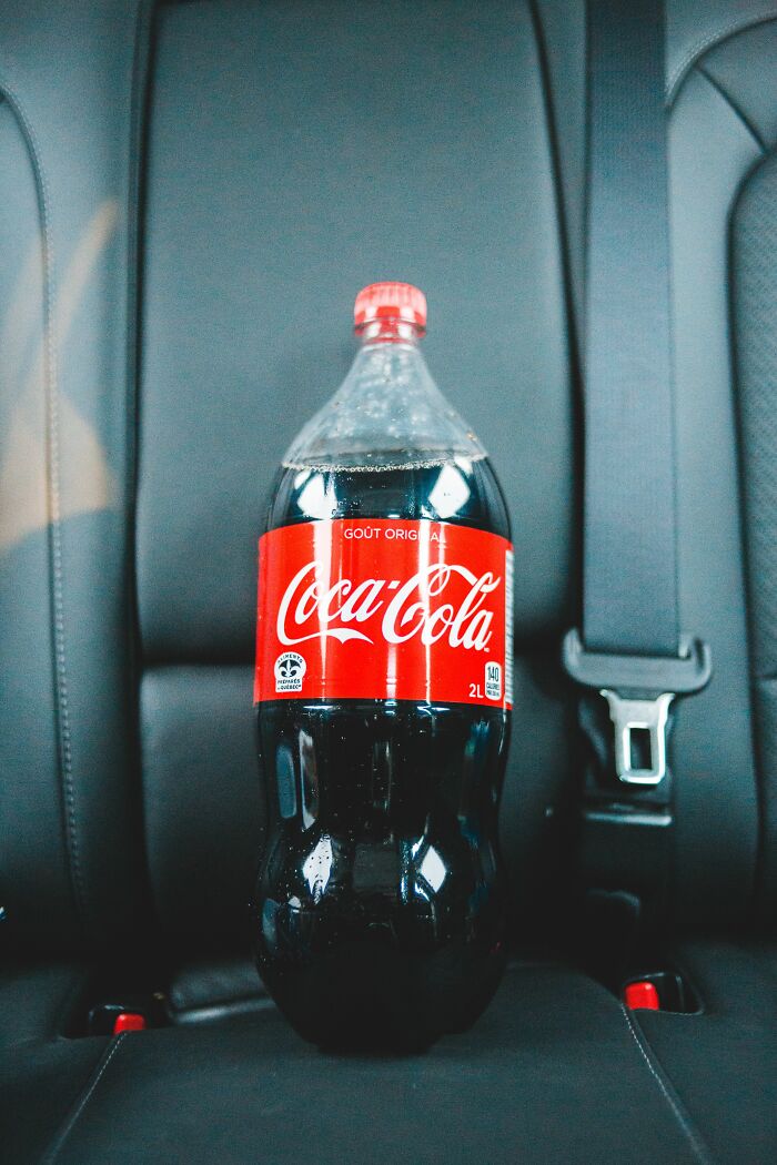 A large bottle of Coca-Cola sitting in a car seat, a common sight in America.