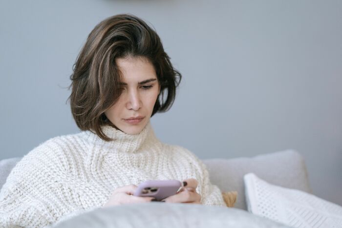 A woman with short hair intently looks at her phone, contemplating she is with the very wrong person.