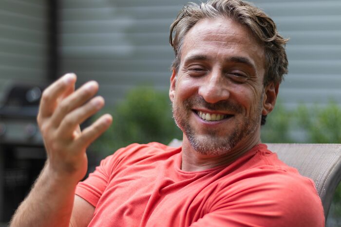 A smiling man in a red t-shirt, delivering sick burns.