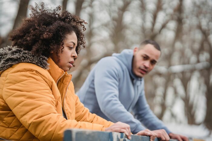 A couple looking unhappy while exercising outdoors, possibly after the boyfriend said something insensitive.
