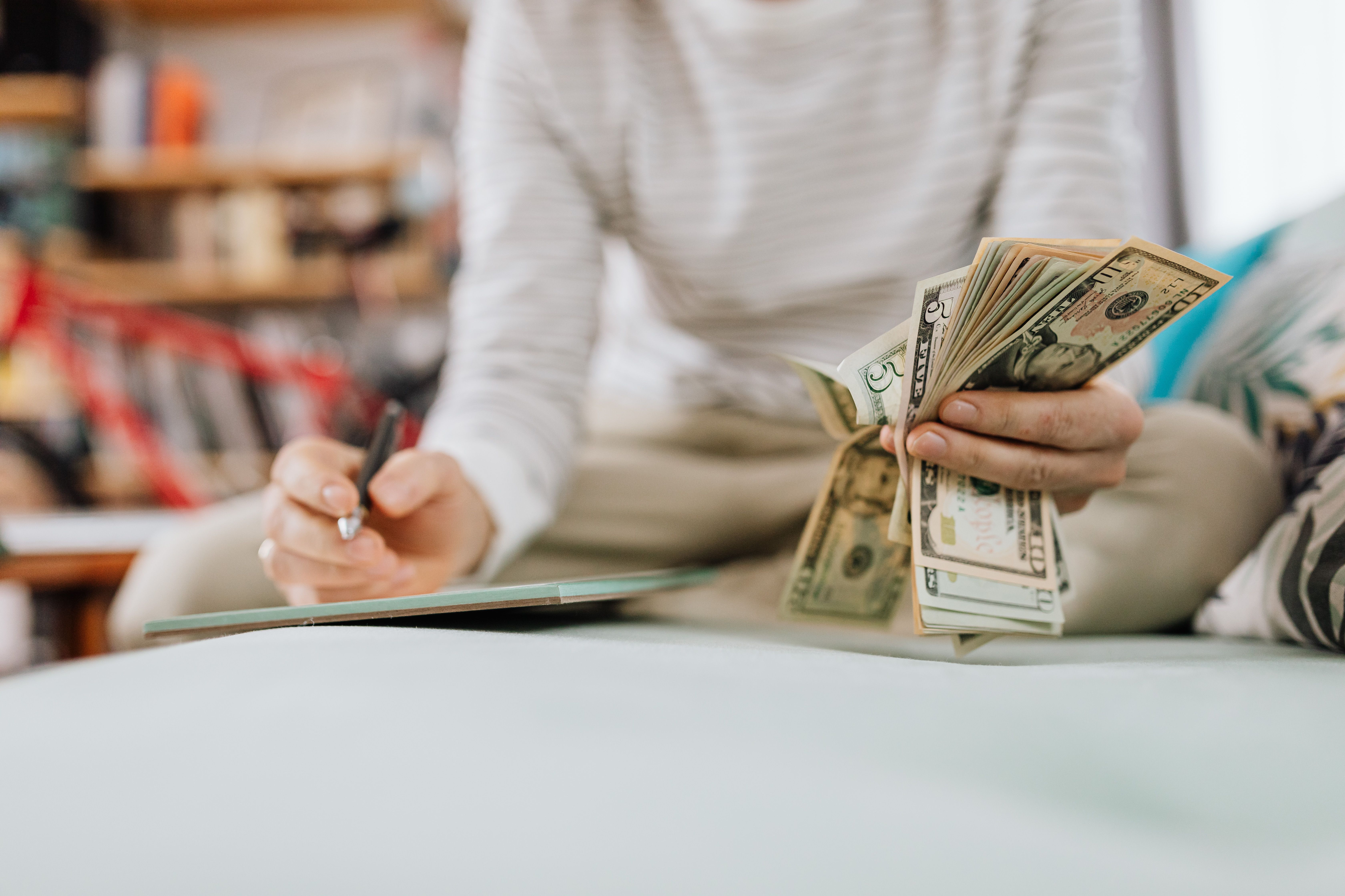 A homeowner holding cash and writing, possibly dealing with HOA fines or finances. A homeowner holding cash and writing, possibly dealing with HOA fines or finances.
