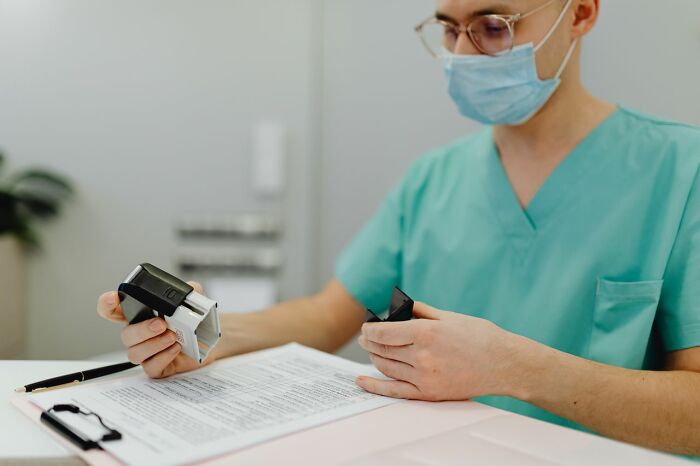 A medical field worker in scrubs and a mask using a stamp on documents, showing administrative tasks.
