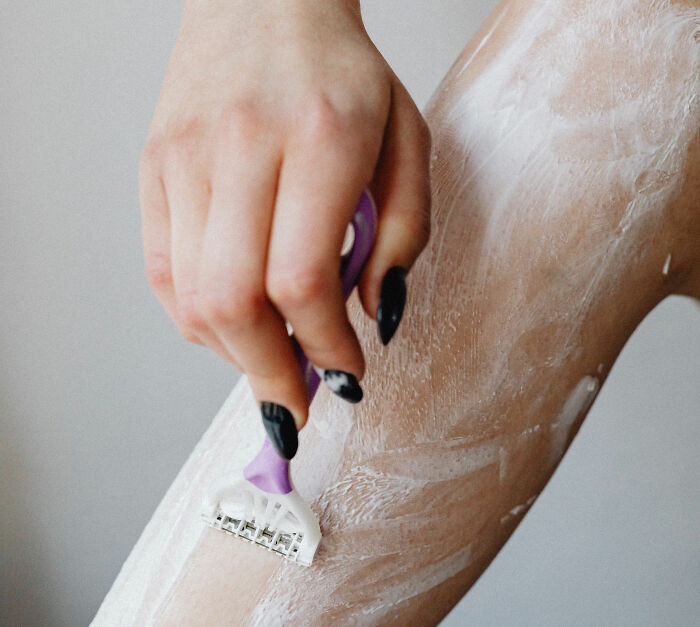 Woman shaving her leg, highlighting the common pre-swim habit linked to flesh-eating bacteria warnings. Woman shaving her leg, highlighting the common pre-swim habit linked to flesh-eating bacteria warnings.