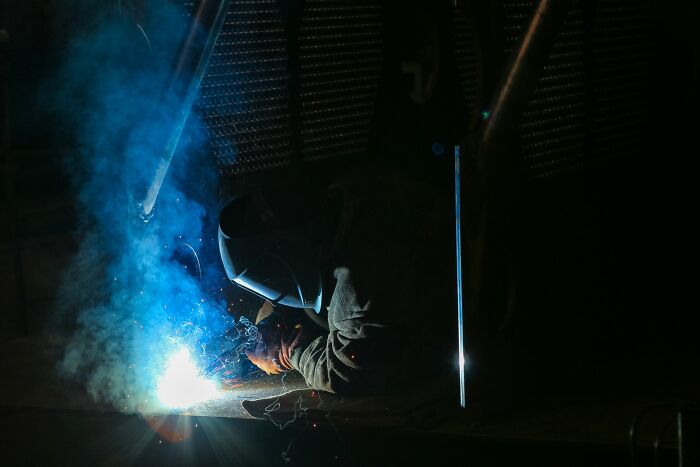A welder at work, representing the intense and transformative experience of life and what comes after.