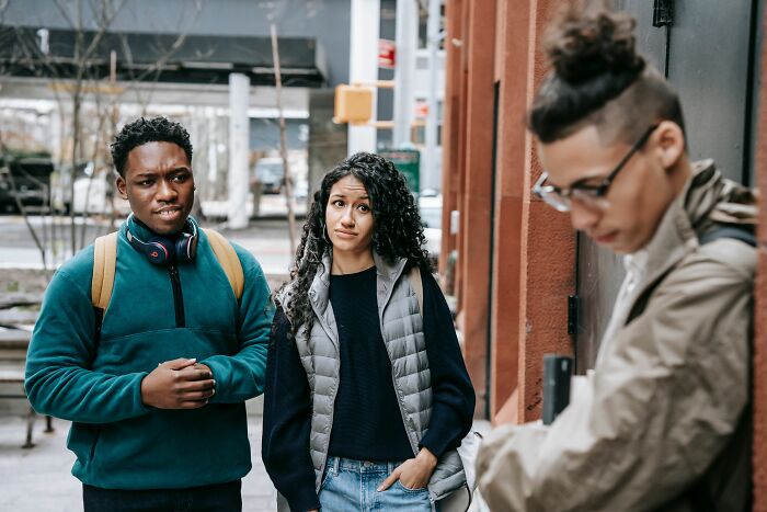 Two people looking confused while a third person delivers sick burns to them on a street.