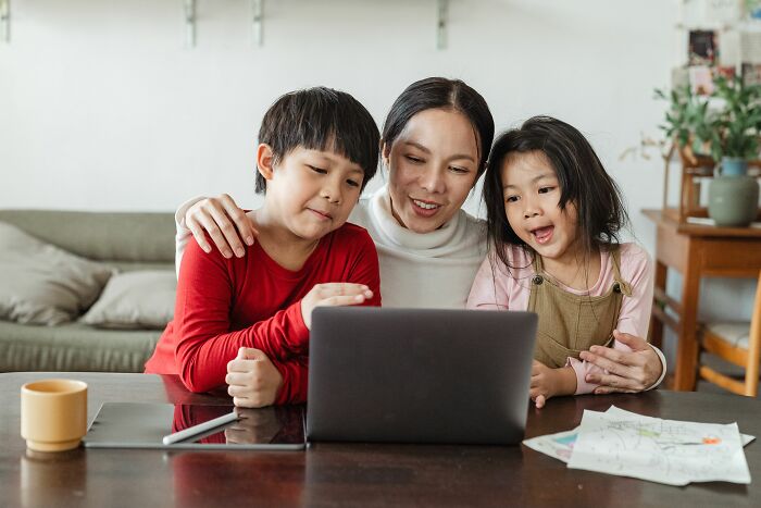 Mother with two children looking at a laptop. Represents incredible accomplishments, family, and motivation.