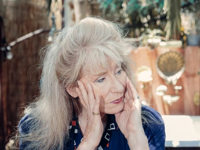 A thoughtful senior woman, looking away, reflecting on being a horrible parent.