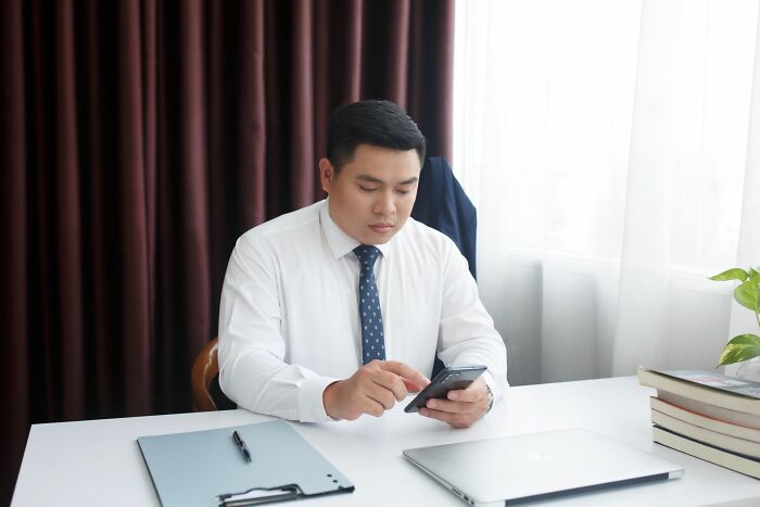 An employee on his phone at a desk, a shocking employee story for HR pros about getting fired.