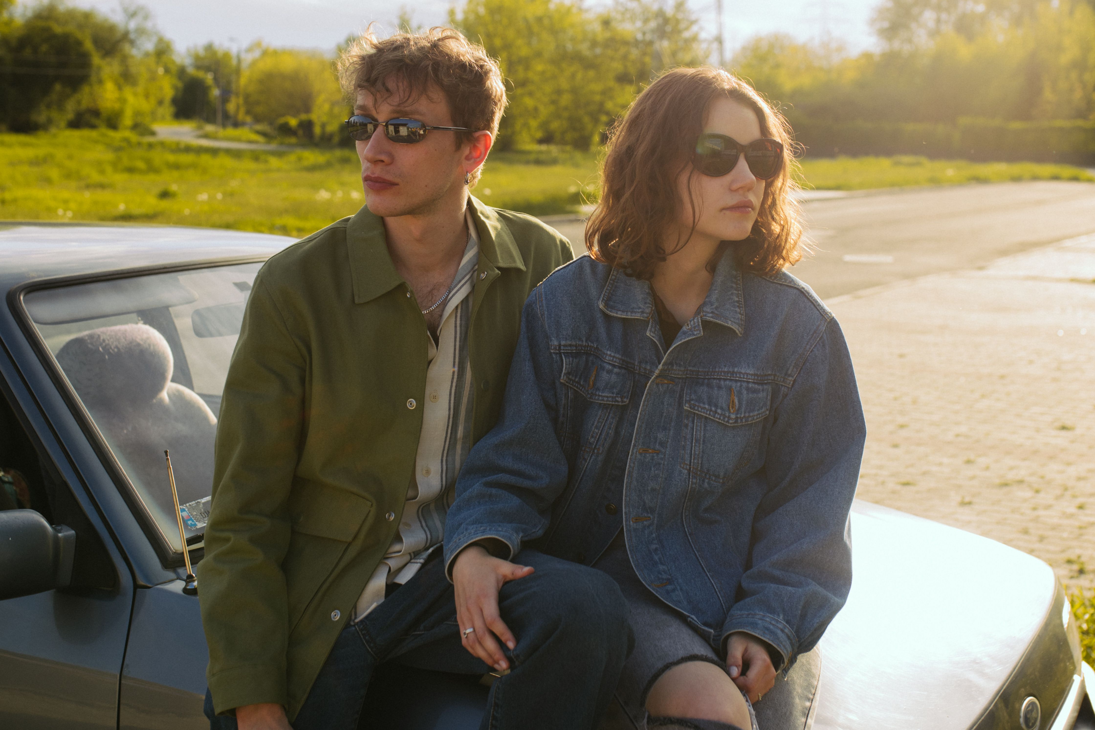 A young couple, the man in a green jacket and the woman in a denim jacket, sitting on a car, related to a wedding dispute. A young couple, the man in a green jacket and the woman in a denim jacket, sitting on a car, related to a wedding dispute.