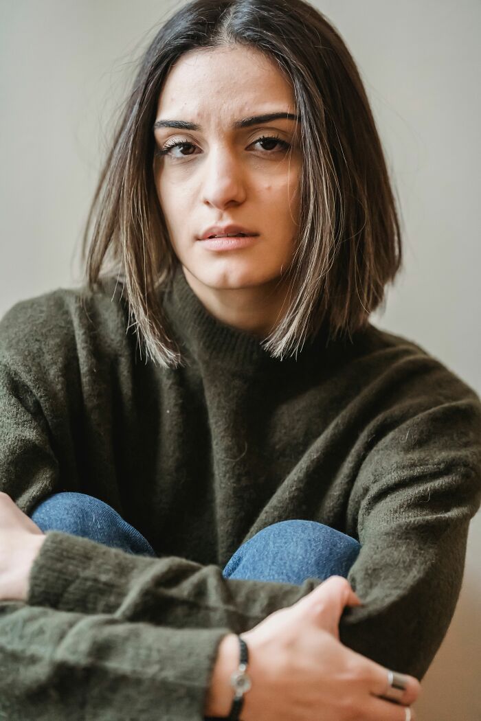 A woman with short dark hair in a green sweater, realizing she's with the wrong person.