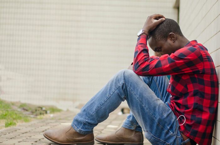 A man sitting on the ground with his head in his hands, highlighting the emotional toll on medical field workers.
