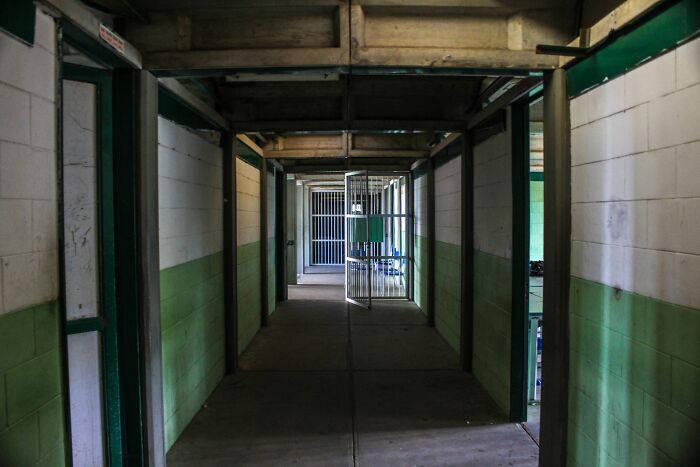 A long, empty prison corridor with green and white walls and open cell doors, highlighting the 100 years in prison sentence. A long, empty prison corridor with green and white walls and open cell doors, highlighting the 100 years in prison sentence.