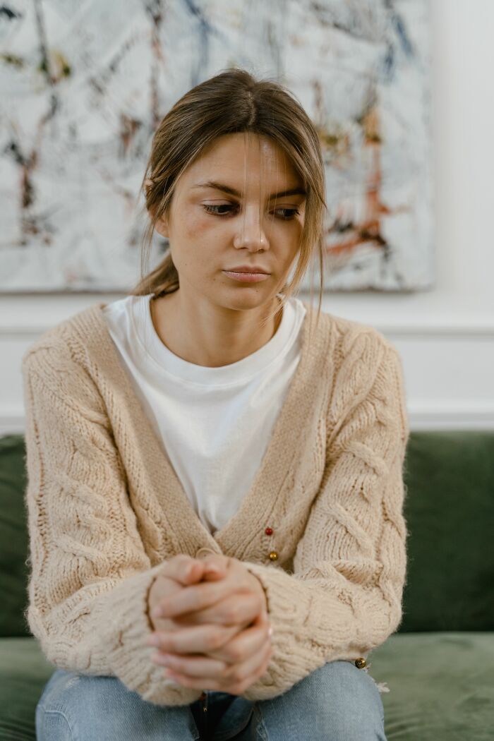 A sad woman with hands clasped, reflecting on a boyfriend's words she could never come back from.