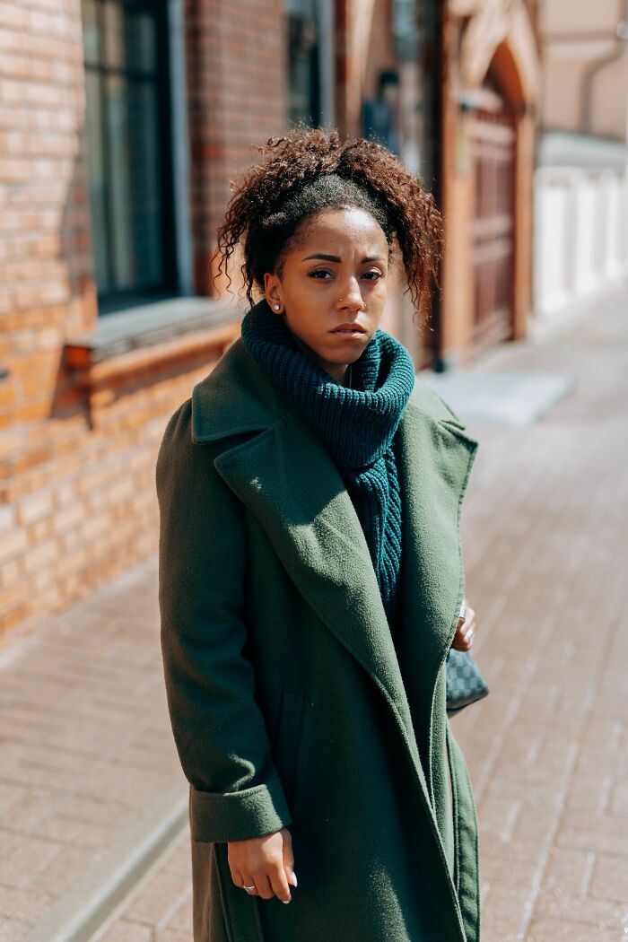 A woman with curly hair wearing a green coat and scarf, delivering a sick burn.