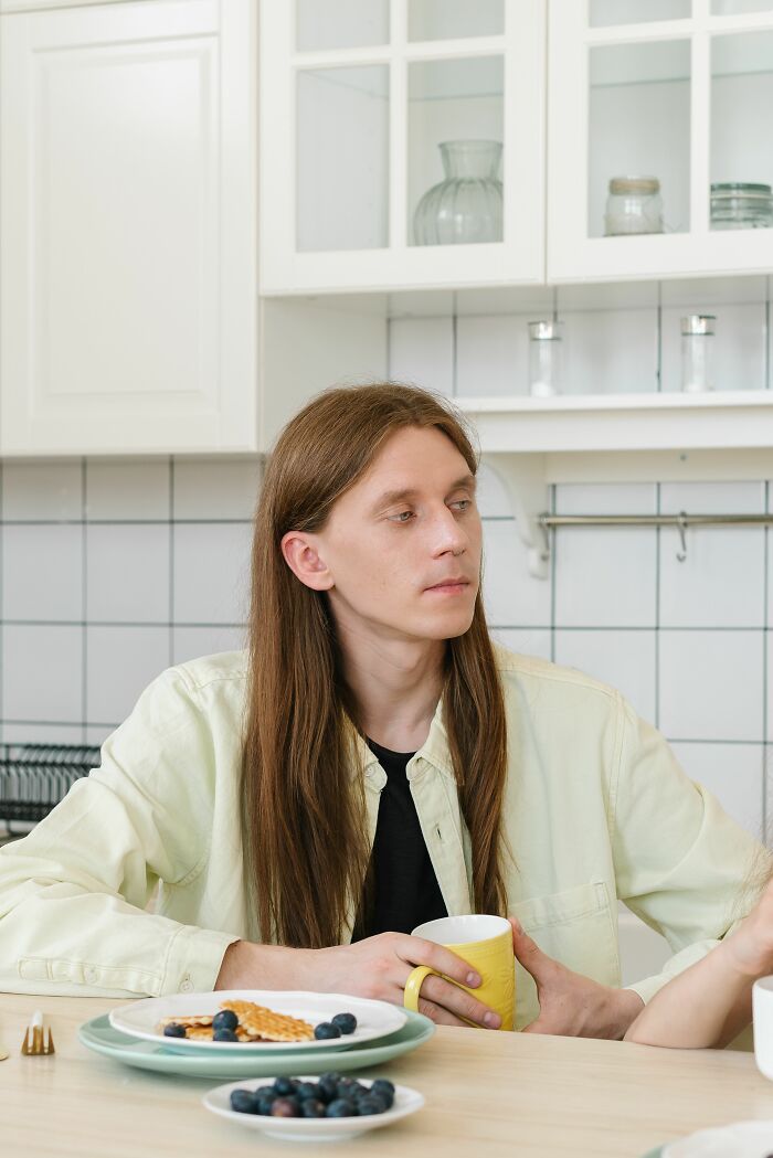 A person with long hair sits at a table, possibly contemplating a sick burn that earned someone mad respect.