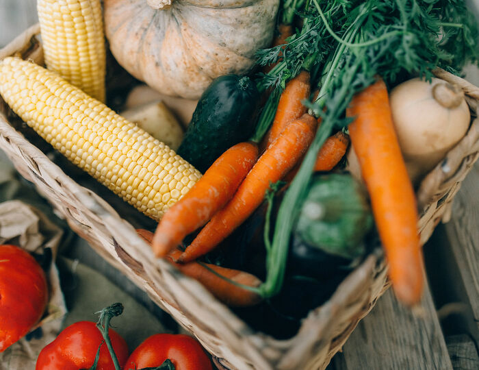 A basket full of fresh vegetables including corn, carrots, and squash, representing healthy school lunch options. A basket full of fresh vegetables including corn, carrots, and squash, representing healthy school lunch options.