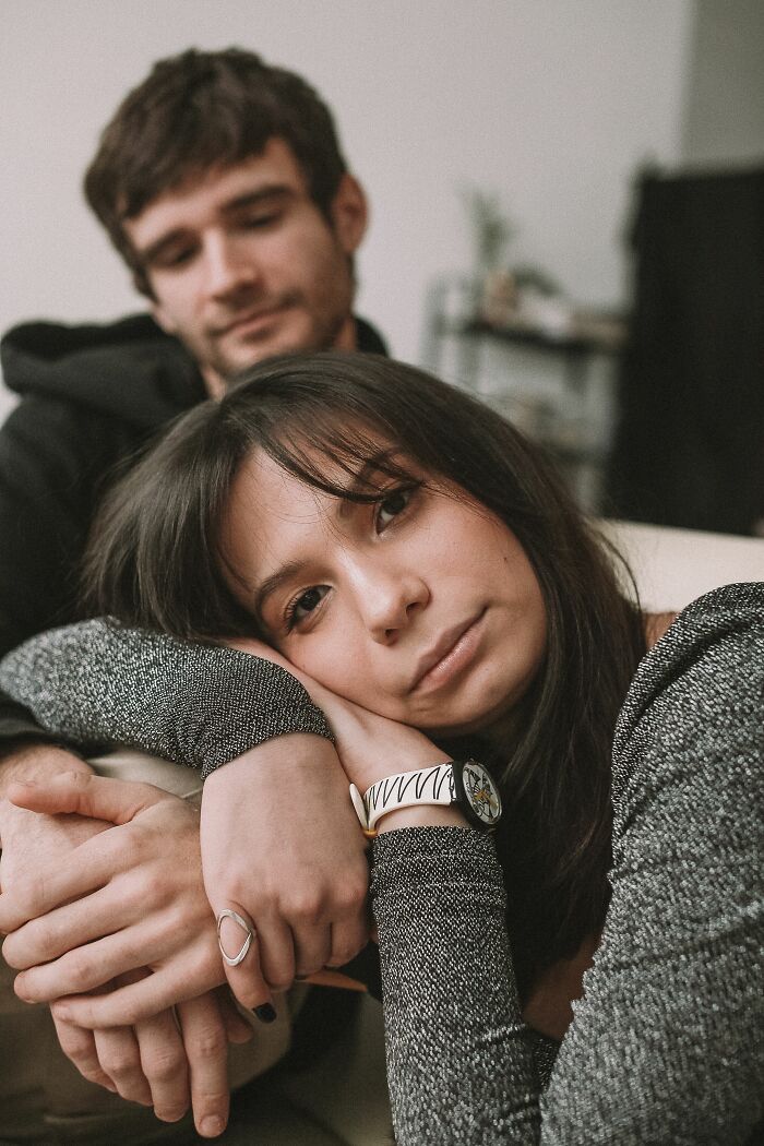 A woman leans on a man's arm, her face reflecting a realization about the wrong person.