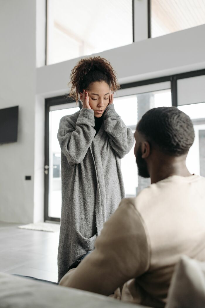 A woman holding her head in distress while talking to a man, emphasizing the exact moment her boyfriend said something.