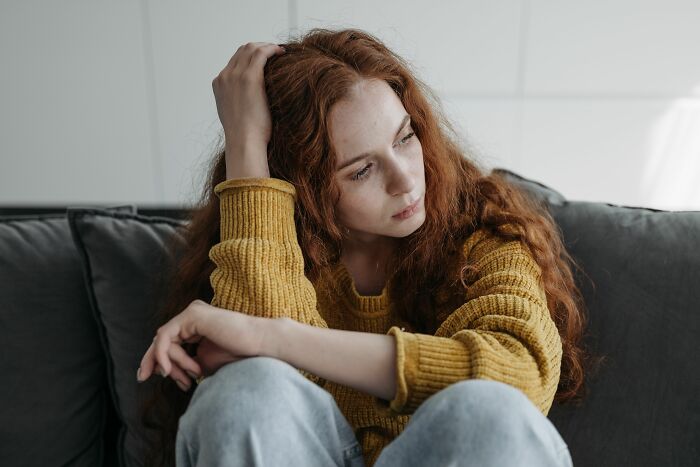 A young woman with red hair looking sad and distant, illustrating a moment she realized they’re with the very wrong person.