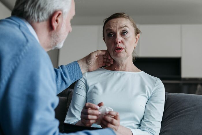 An older man comforts a crying woman holding a tissue, discussing horrible parent experiences.