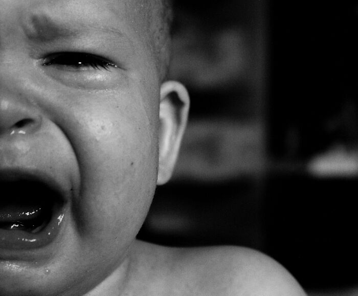 Black and white close-up of a crying baby, depicting the distress of a baby granddaughter left in a hot car. Black and white close-up of a crying baby, depicting the distress of a baby granddaughter left in a hot car.