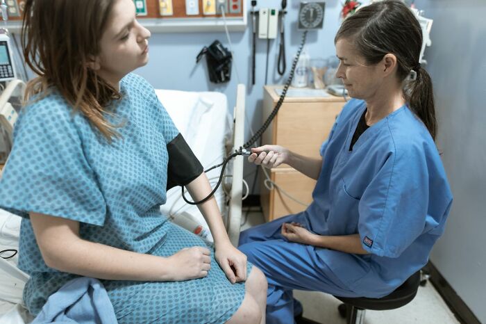 A medical field worker takes the blood pressure of a patient in a hospital room, highlighting their care.
