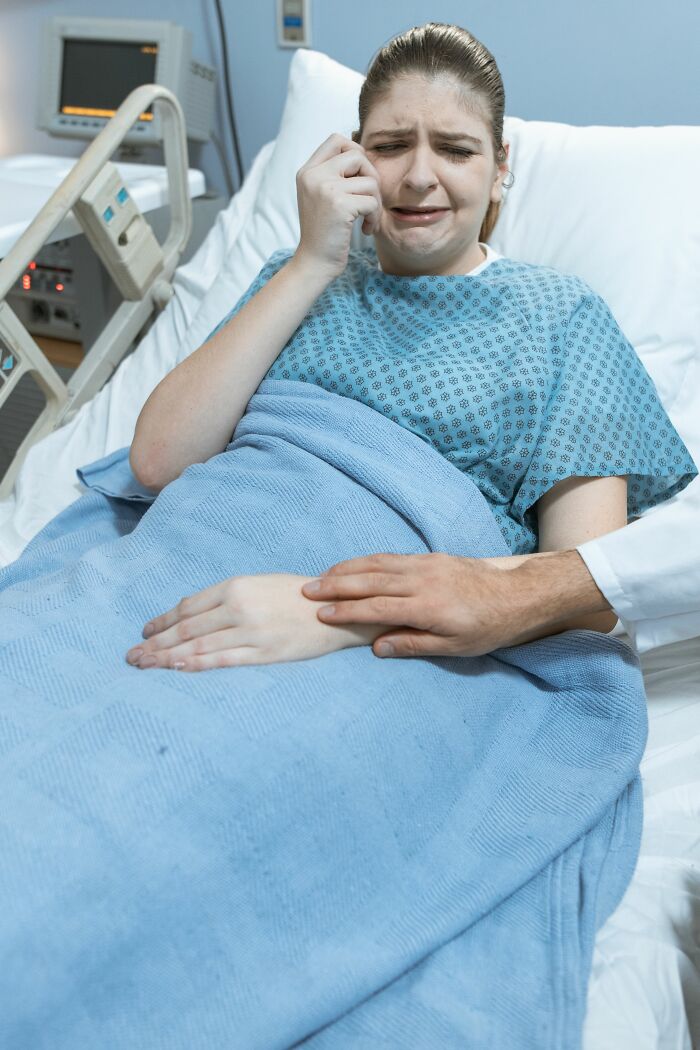 A woman crying in a hospital bed, being comforted by a hand, illustrating the moment her boyfriend said something she could never come back from.