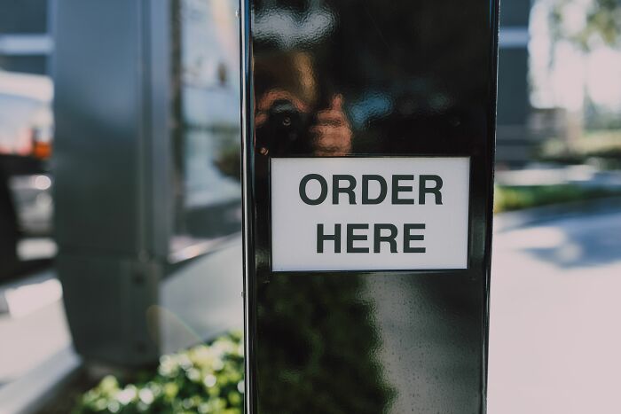An 'ORDER HERE' sign at a drive-through, capturing the initial interaction point for customers and employees.