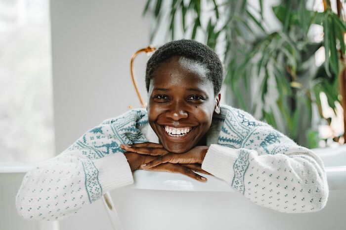 A smiling woman in a sweater, representing incredible accomplishments and motivation.