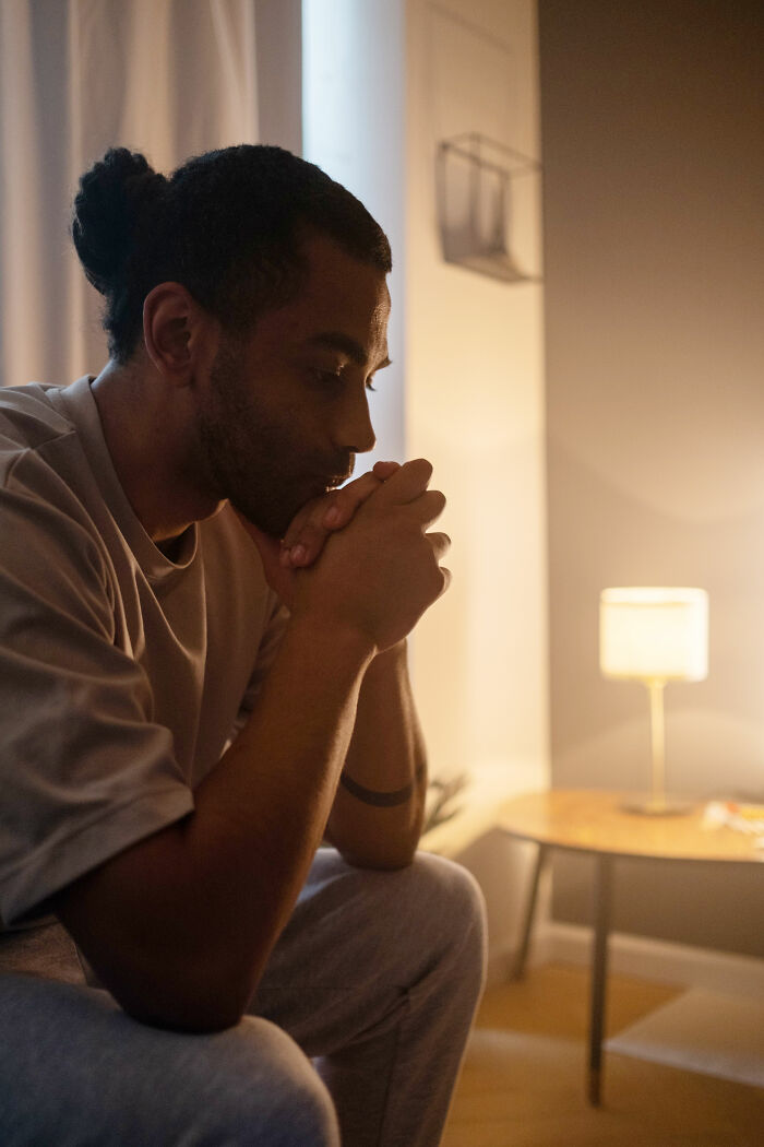 A man with a bun, sitting alone, contemplating, realizing he's with the very wrong person.
