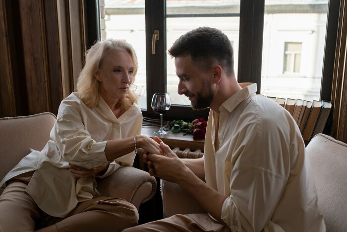 A man holding a woman's hand, sharing spicy personal details or private thoughts.