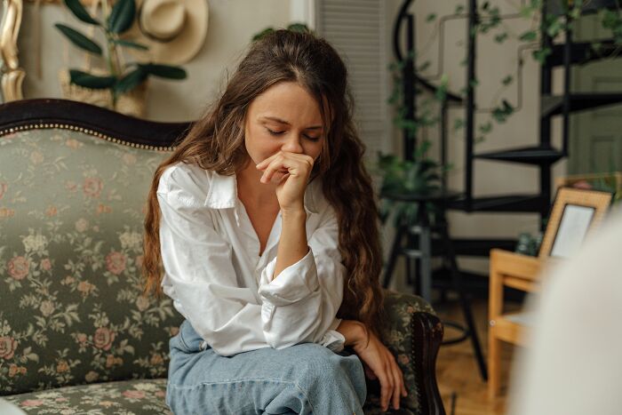 A young woman on a couch looking distraught, realizing she is with the very wrong person.