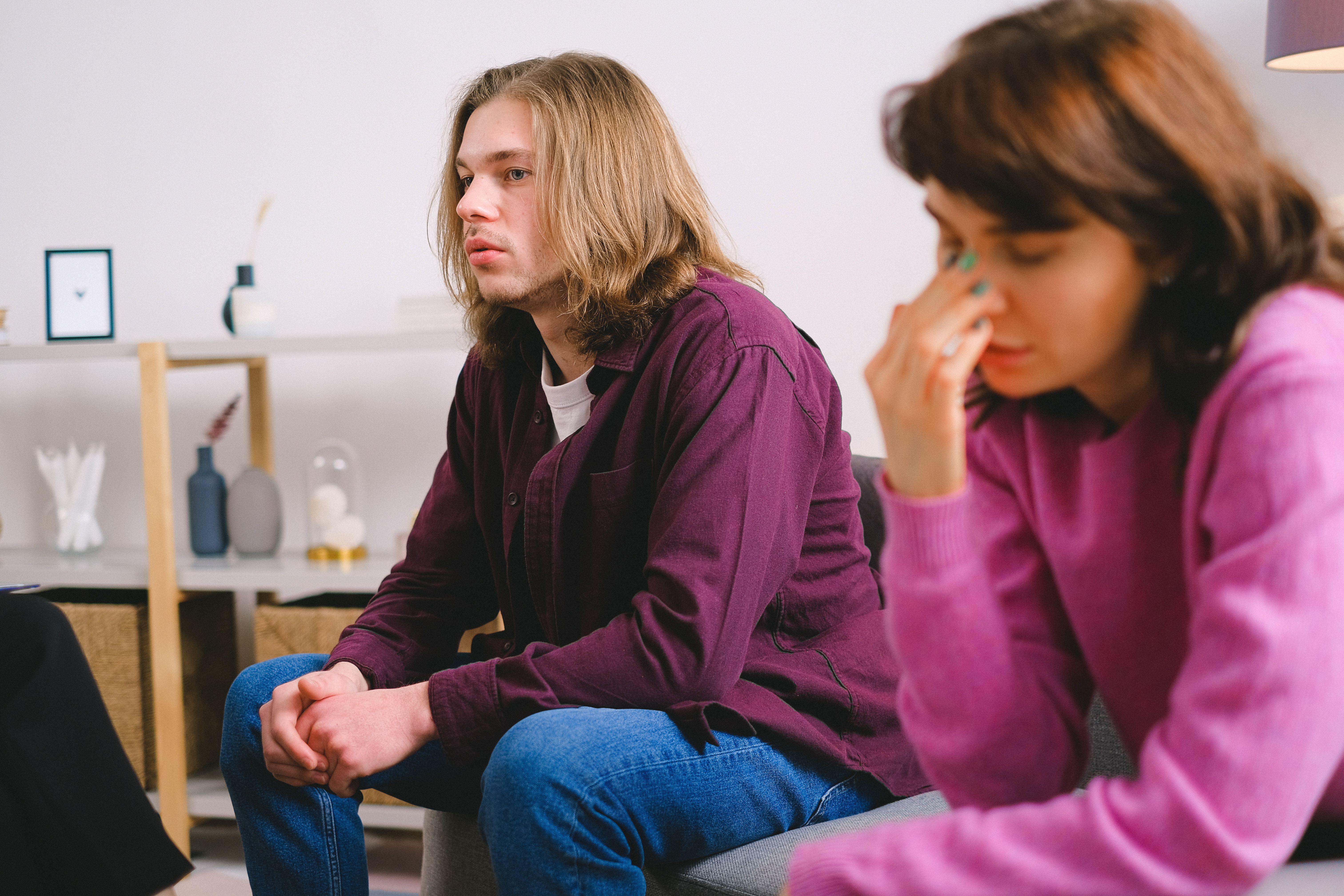 A couple sits uncomfortably during a therapy session, reflecting a family wedding dispute. A couple sits uncomfortably during a therapy session, reflecting a family wedding dispute.
