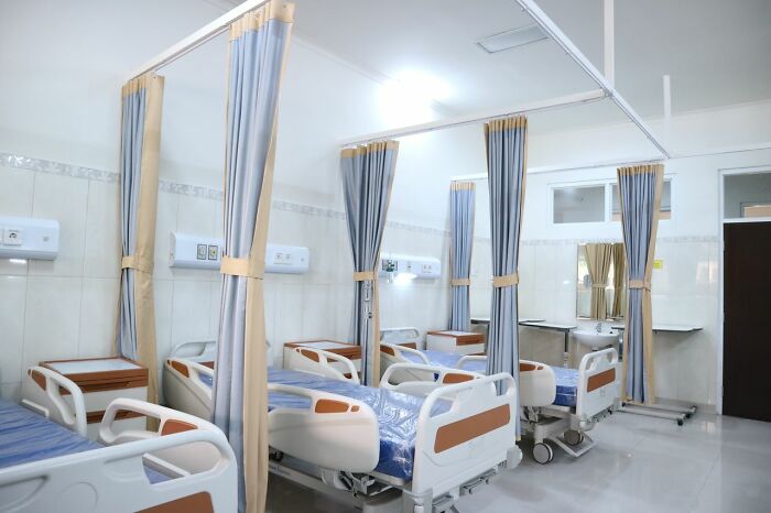 An empty hospital room with multiple beds, representing the environment medical field workers operate in.