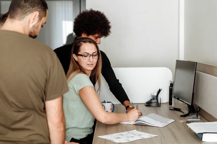 Coworkers collaborating at a desk, hinting at sharing personal details or discussing PTSD.