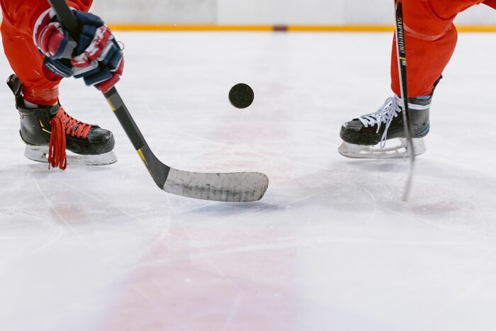 A close-up of a hockey player hitting a puck, showcasing the fast-paced nature of sports in America that took newcomers by surprise.