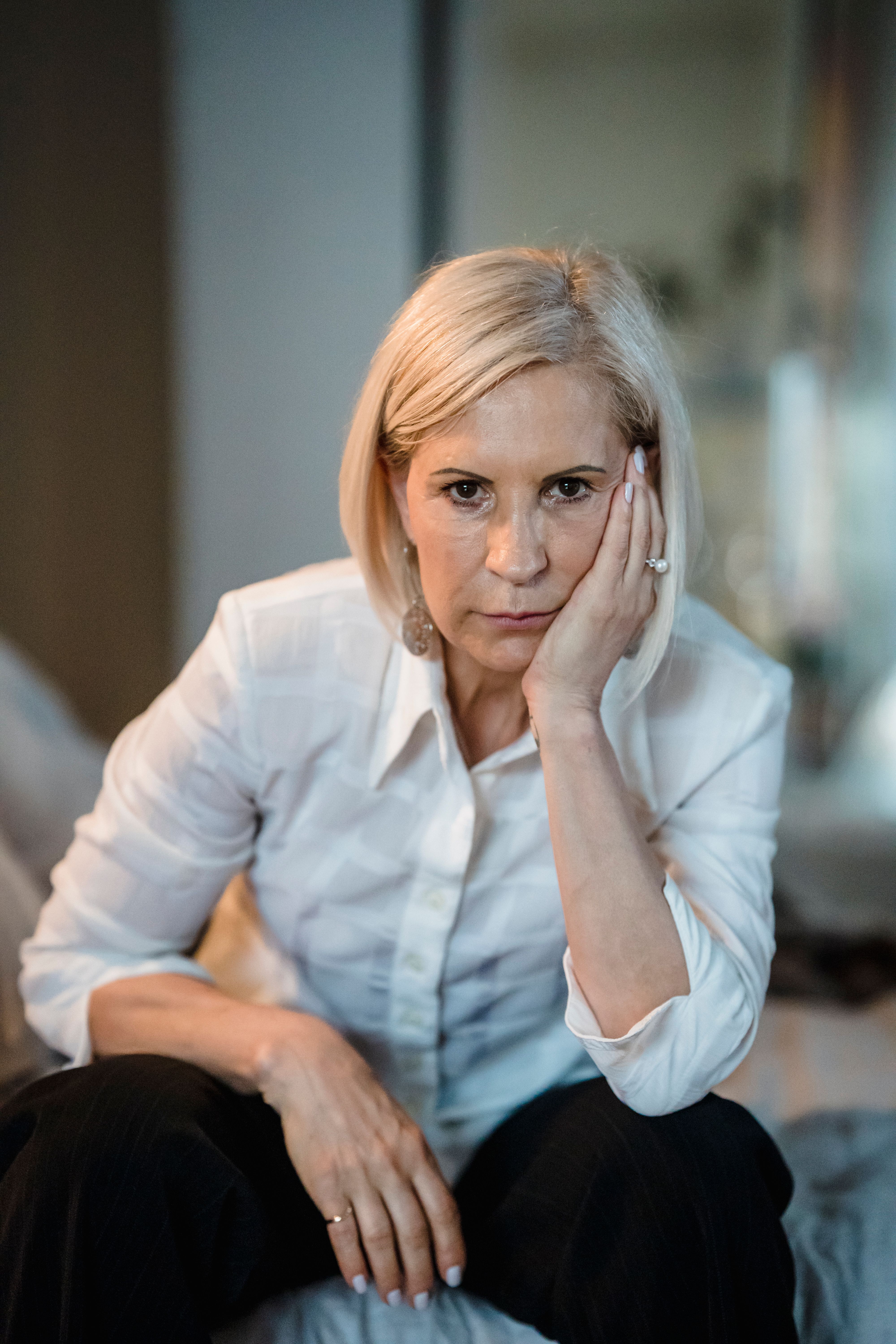 A woman with blonde hair, dressed in white, looking upset, symbolizing the emotional toll of a wedding dispute.