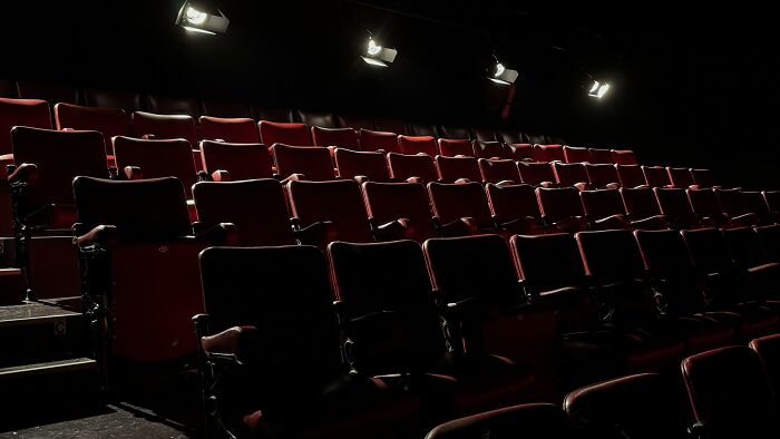 Empty cinema showing rows of red seats in the dark, highlighting famous movies ending scenes, ideal for cinephile movie fans.