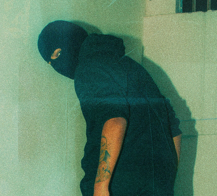 A man in a balaclava, symbolizing the man next to the bed incident, urging Bali travelers to be careful.