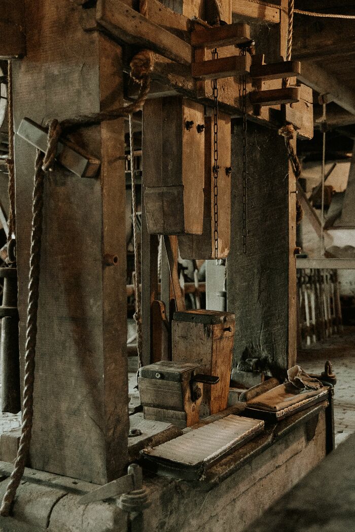 An old, rustic wooden machine with ropes and chains in a dimly lit industrial setting. People believe today that propaganda influences beliefs.