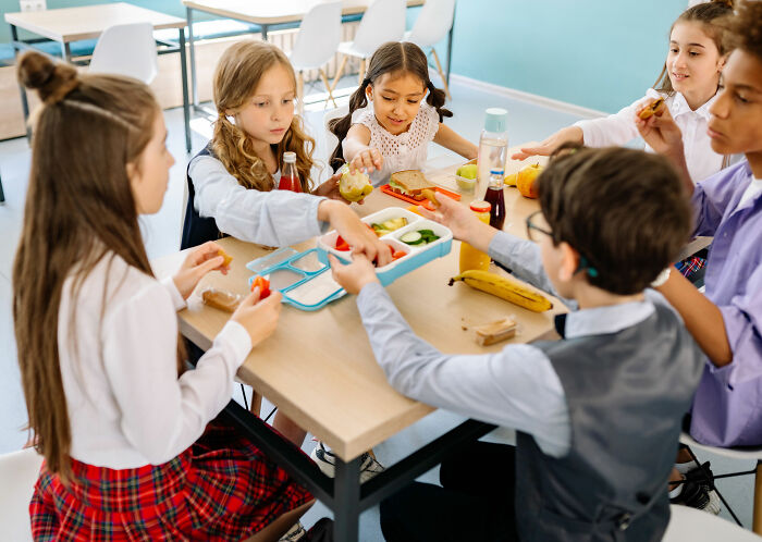 Kids enjoying a school lunch, likely in France, featuring diverse foods. Kids enjoying a school lunch, likely in France, featuring diverse foods.