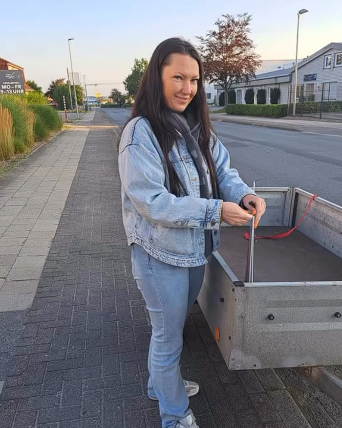 A Conservative politician stands next to a trailer, looking at the camera, with a provocative necklace visible on her campaign poster. A Conservative politician stands next to a trailer, looking at the camera, with a provocative necklace visible on her campaign poster.