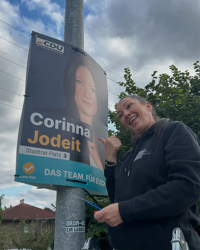 A smiling conservative politician Corinna Jodeit on a ladder, posing next to her campaign poster with the provocative necklace. A smiling conservative politician Corinna Jodeit on a ladder, posing next to her campaign poster with the provocative necklace.