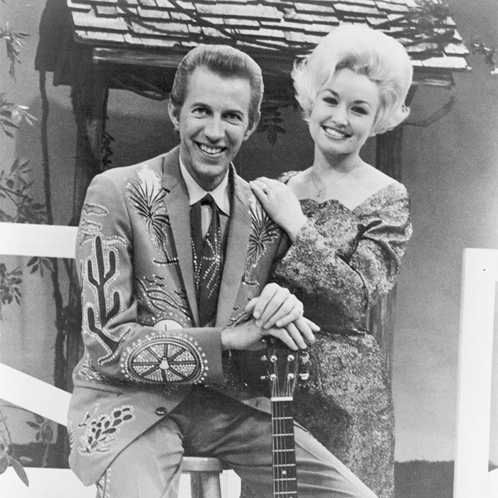 Black and white image of Dolly Parton smiling with Porter Wagoner, symbolizing resolved feuds and controversies.