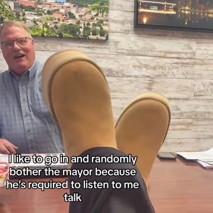 A person with their feet on a desk, talking to a man, a funny meme about bothering the mayor.