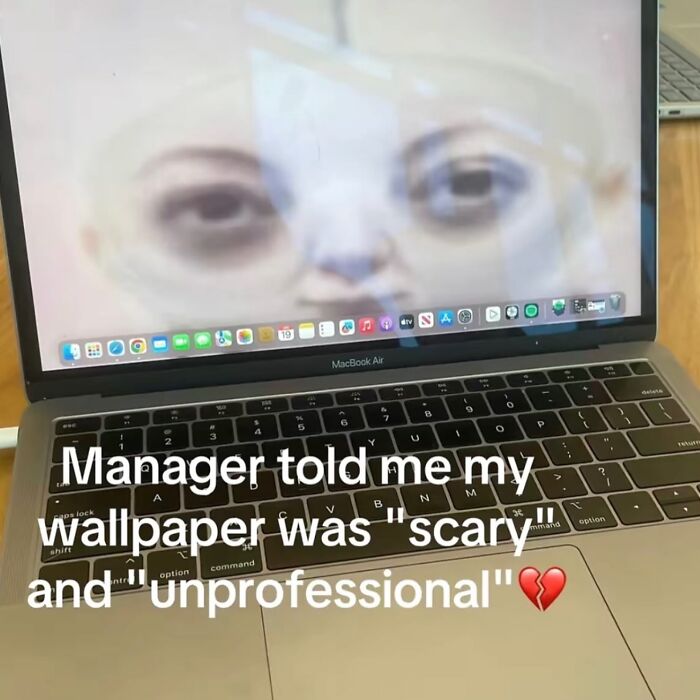A MacBook Air with a scary and unprofessional wallpaper, showing a close-up of a ghostly face, one of many hilarious memes.